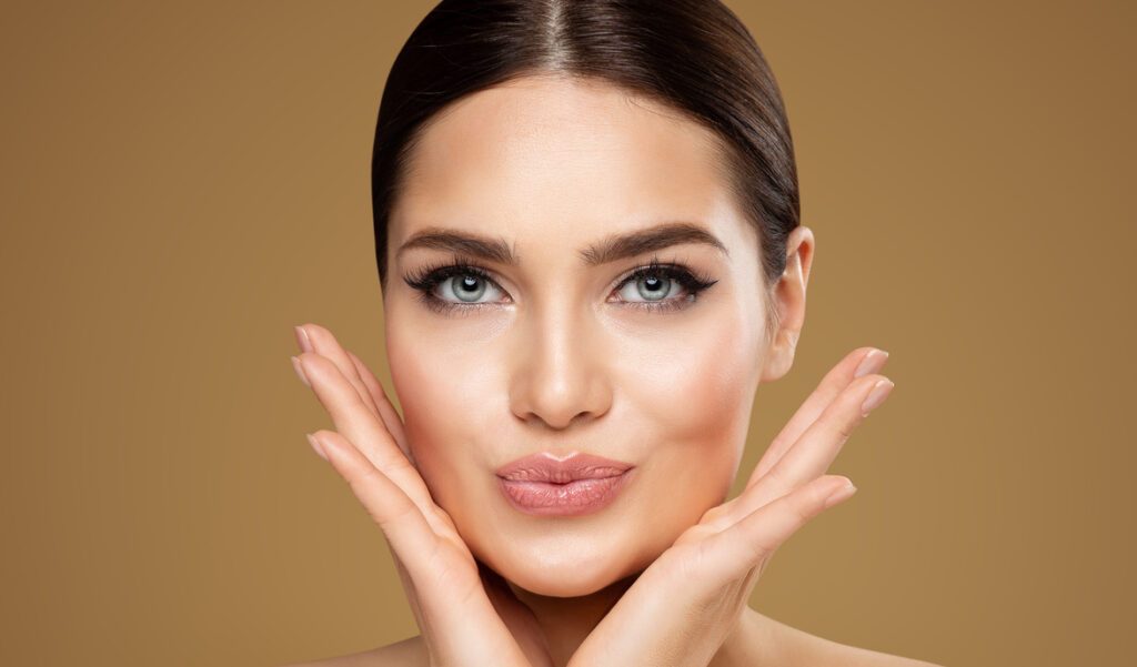 Attractive Woman framing face with palms with luscious lips - lip injections Boca Raton